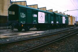 Vagón cerrado metálico de ejes en color verde con anagramas de “Mercedes” y “Cargas - Renfe”