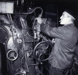 Interior de una cabina de conducción de una locomotora de vapor, y maquinista conduciendo.