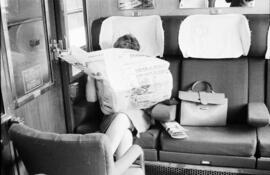 Interior de un coche de viajeros de la SNCF con una mujer sentada leyendo el periódico