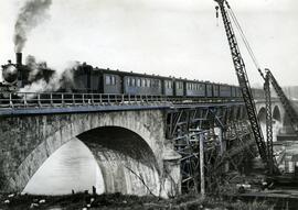 Tren pasando por un puente en restauración que fue destruido en la guerra