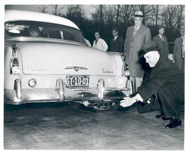 El presidente de la Corporación Chrysler comprueba el tubo de escape de un coche deportivo Plymou...