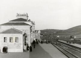 Vista de la estación de Santiago. En primer término, viajeros esperando y al fondo, señales de sa...