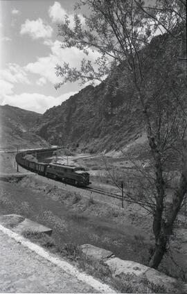 Composición de locomotora eléctrica y vagones abiertos circulando por terrenos de Villamanín, en ...