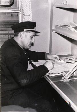 Jefe de tren de RENFE uniformado en su cabina, cumplimentando la documentación exigida para la ex...