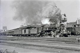 Locomotora de vapor 231 - ? con penacho de humo remolcando un tres con coches de viajeros en la e...