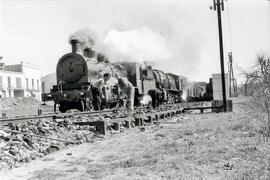 Trabajadores ferroviarios en la vía con llave de tirafondos y a su lado una composición en vía de...