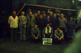 Grupo de personas posando junto a locomotora de vapor, entre ellas dos mujeres trabajadoras de RE...