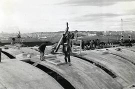 Vista en primer plano de personal trabajando en la construcción del tejado del nuevo depósito par...