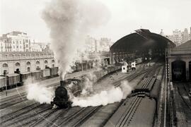 Composición de mercancías remolcada por locomotora de vapor saliendo de la estación de Valencia -...
