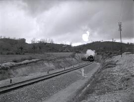 Composición de viajeros remolcada por locomotora de vapor, circulando por la línea de Madrid a Ir...