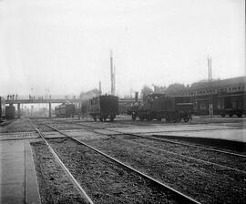 Coches de viajeros de dos ejes, vagones y locomotora de vapor con rodaje 120 en vías de la estaci...