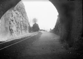 Locomotora de vapor remolcando una composición y entrando en un túnel sin identificar