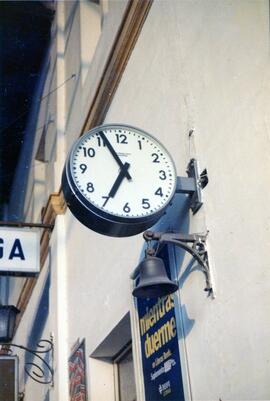 Reloj de andén tipo sandwich de Relojería Suiza (Madrid), campana y cartel en una estación sin id...